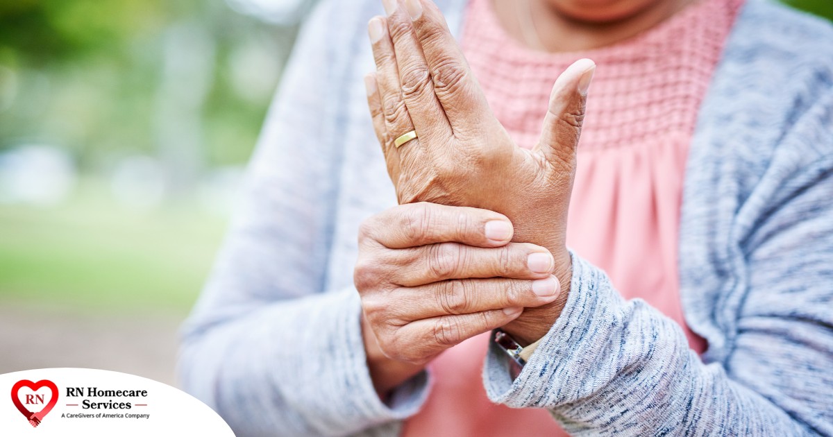 A senior woman holds her hand in pain, representing arthritis and what Arthritis Awareness Month can help with.